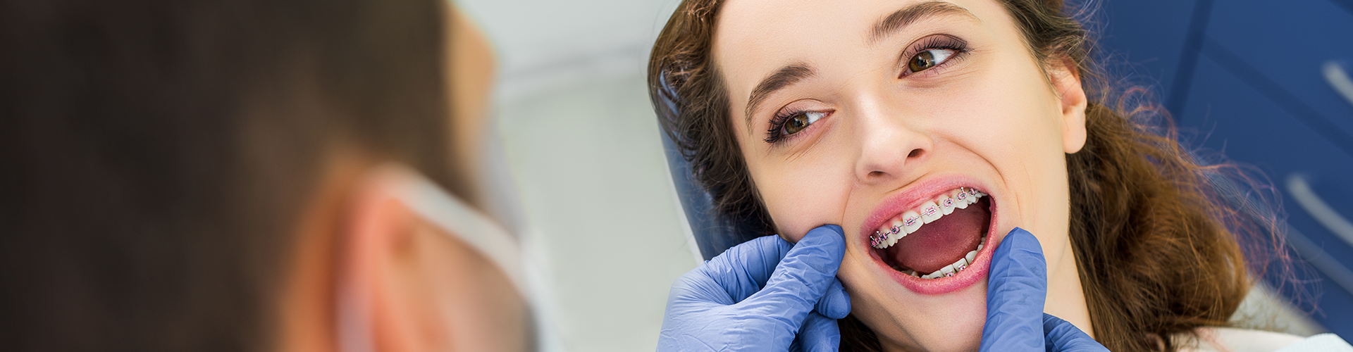 gloved hands framing mouth of girl wearing braces